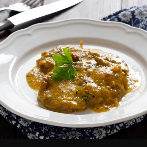Scaloppina allo zafferano servita nel piatto con salsa gialla