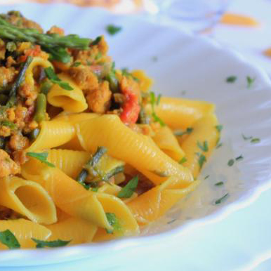 Garganelli con asparagi selvatici, salsiccia e zafferano serviti nel piatto