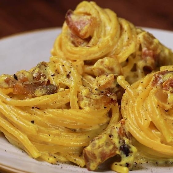 Spaghetti alla crema di ricotta e zafferano con guanciale croccante serviti nel piatto